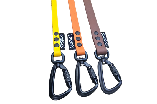 A selection of DoggoZ handleless BioThane drag lines in yellow, orange, and brown. The photo showcases the high-quality matte finish of the BioThane material, paired with heavy-duty black locking carabiners and durable rivets. These snag-resistant leashes are designed to give dogs freedom during hiking and off-leash training while ensuring safety.