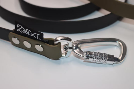 Close-up of high-quality silver locking carabiner hardware attached to an olive green and black BioThane dog leash with the DoggoZ brand label.