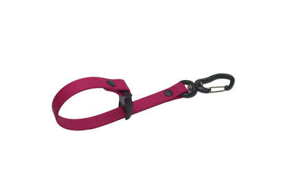 Handmade pink BioThane leash keeper with a secure black carabiner and quick-release buckle by DoggoZ. This practical leash holder allows dog owners to easily carry or store their leash hands-free. Made from authentic, waterproof BioThane with matte black rivets, perfect for adventure-ready dog gear organization.