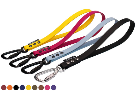 A lineup of DoggoZ SAFE Short Dog Leashes (Traffic Handles) in yellow, magenta, light blue, and black BioThane. Featuring both silver and black locking carabiners for high-traffic safety. Showing a choice of multiple colors: wine red, orange, black, navy blue, sunflower yellow, olive green, brown, magenta pink, purple.